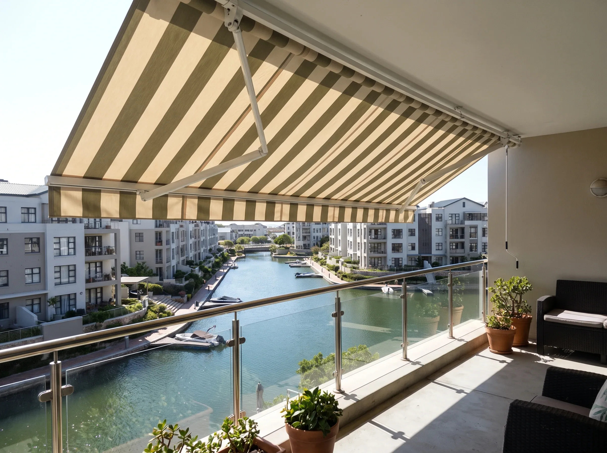 Striped folding-arm fabric awning extended over a Century City apartment balcony above the canal